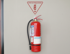 Wall-mounted red fire extinguisher displayed under a clearly marked fire extinguisher sign with a downward arrow - fire extinguisher symbols