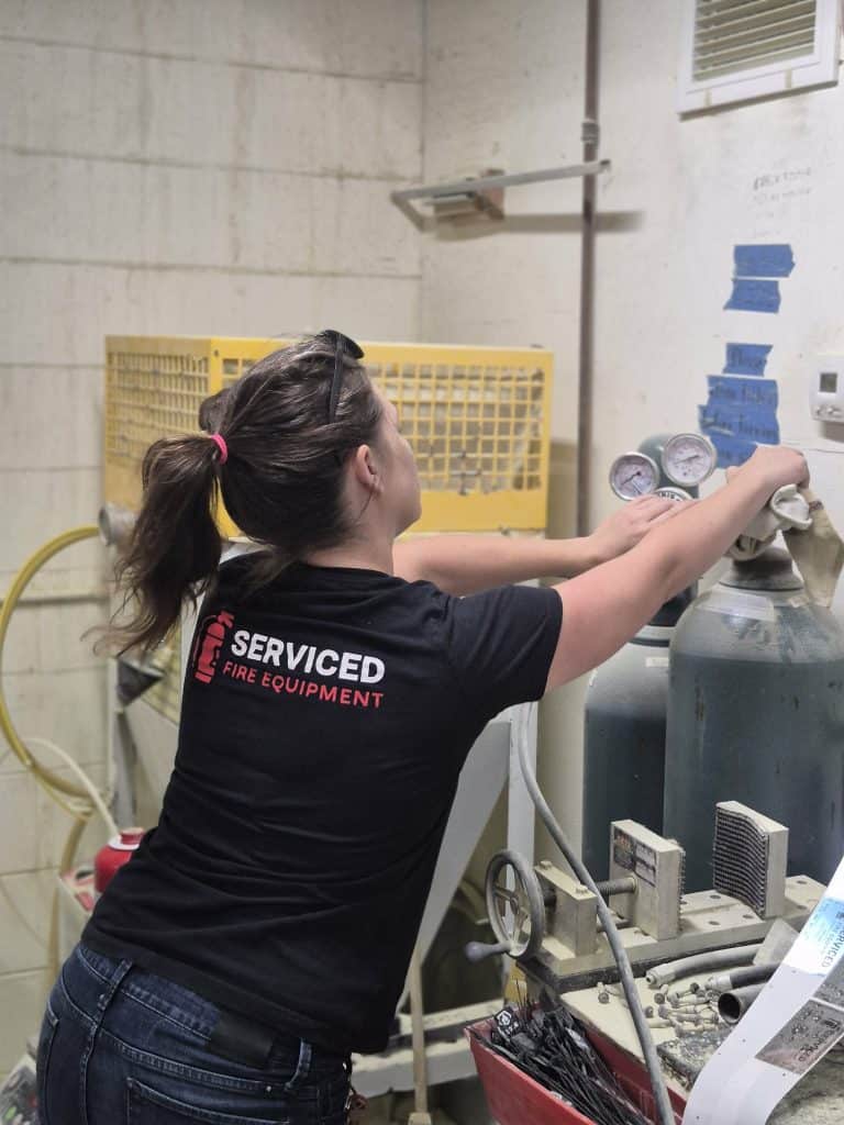 Technician recharging fire extinguishers at Serviced Fire Equipment in St. Petersburg, FL